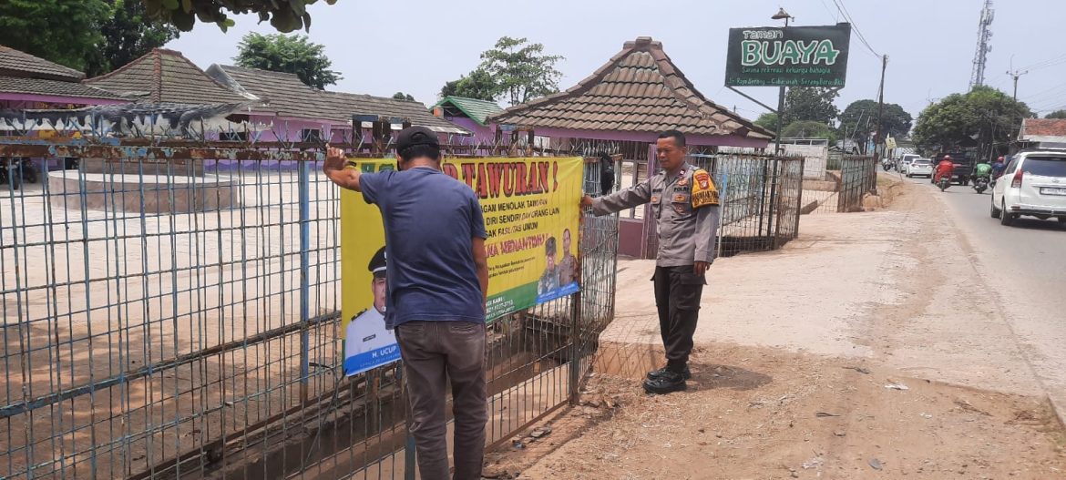 Bhabinkamtibmas Polsek Serang Baru bersama Pemerintah Desa Sukaragam Pasang Spanduk Anti Tawuran